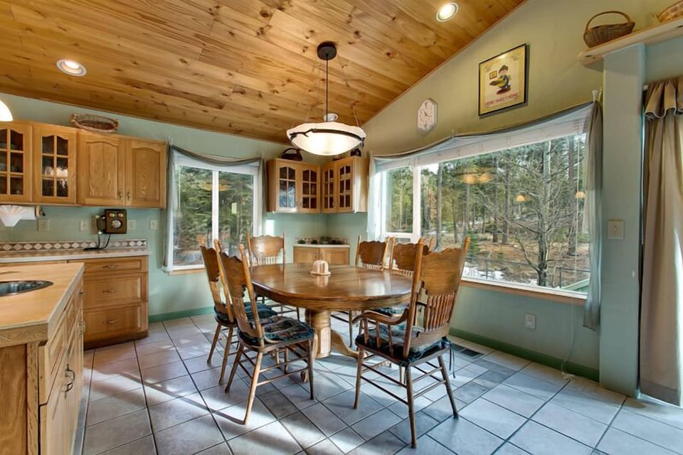 Beautiful dining area with large windows, offering stunning wooded views and plenty of seating.