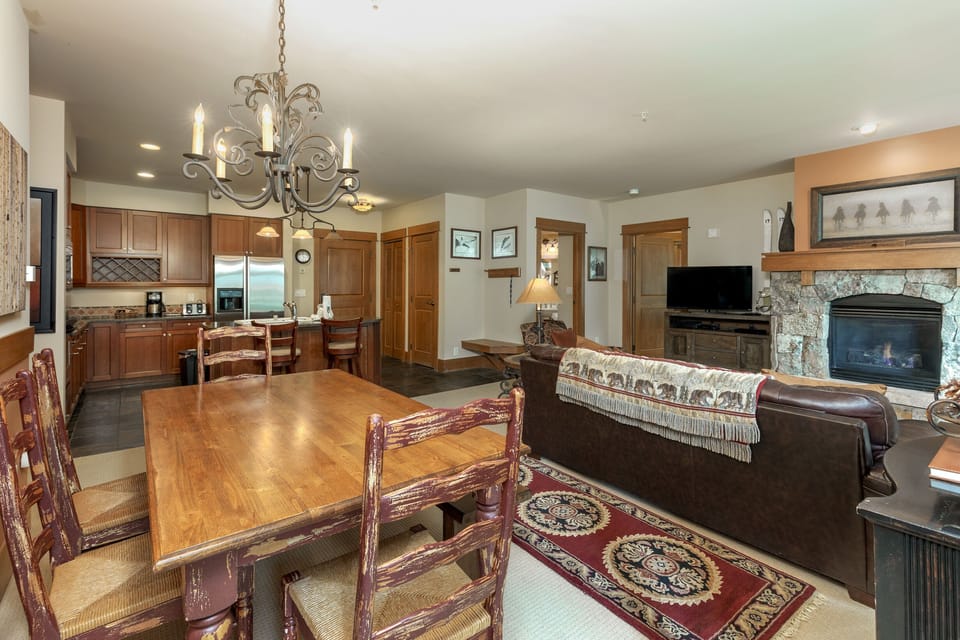 Relax in your elegant open-plan living space with stone fireplace, full kitchen, and dining for eight under a stunning chandelier.