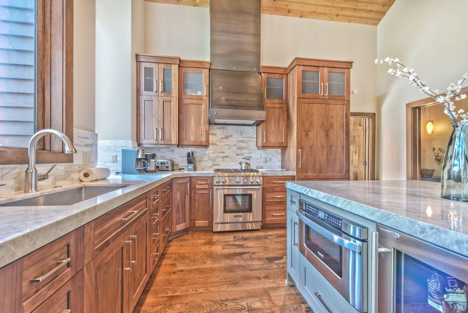 Fully Equipped Gourmet Kitchen with High-end Finishes, Quartz Countertops, Thermador Refrigerator and 4-Burner Gas Stove, Stainless Steel Appliances, Bar Seating for 5 and Powder Room