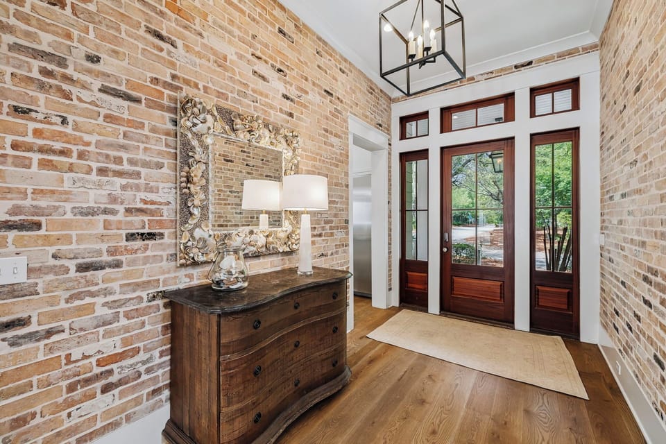 Step through the welcoming double doors into your stylish entryway, where rustic brick walls and warm wood floors create an inviting first impression that sets the tone for your entire stay.