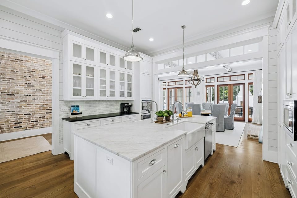 Gather around a spacious marble island perfect for meals or morning coffee. White cabinetry, pendant lighting, and warm wood floors create an inviting space where you'll love cooking and connecting.