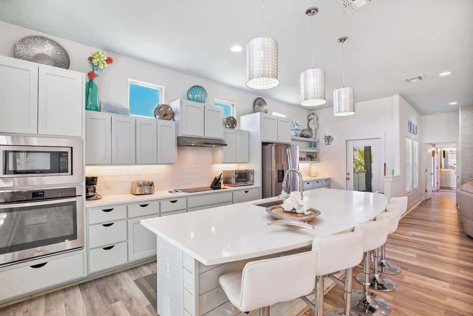 Gourmet Kitchen — Gray Cabinets, Quartz Island with White Bar Stools & Drum Pendant Lights