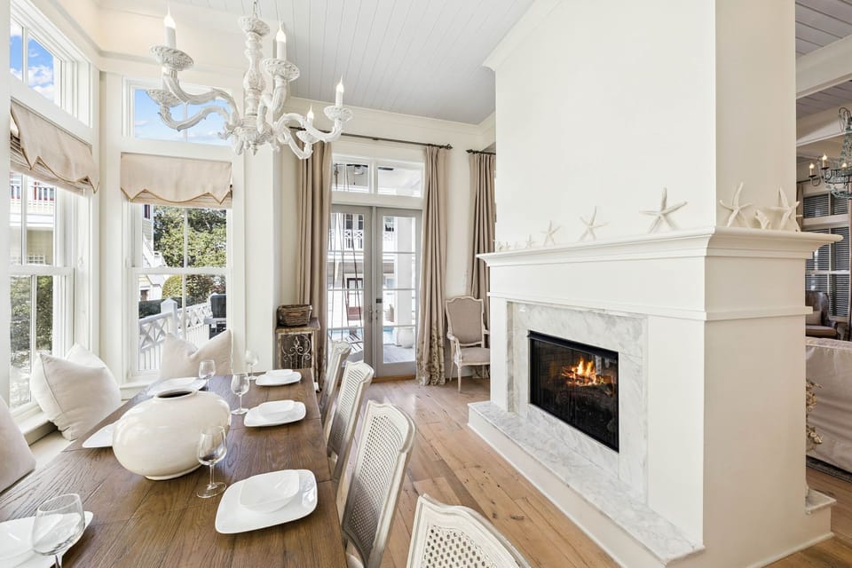 Gather around your elegant dining table where coastal charm meets luxury, with a crackling fireplace creating perfect ambiance for memorable meals.