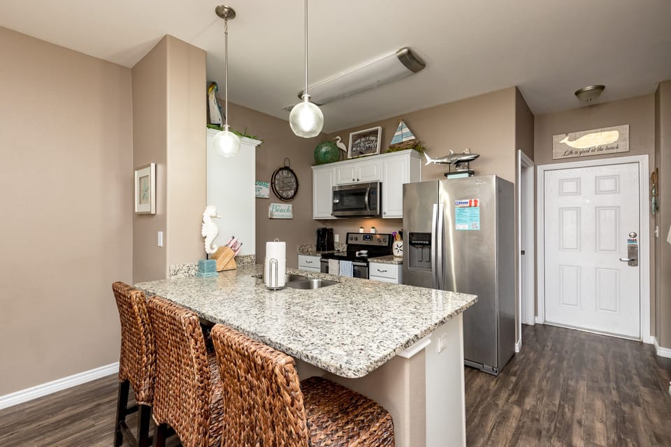 Your spacious kitchen features granite counters, full appliances, and coastal-themed decor that sets the perfect stage for vacation meal prep.