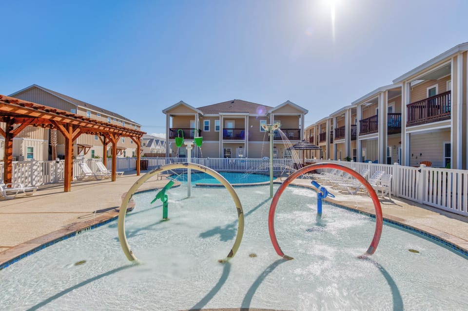 Splash zone with colorful water hoops and sprays creates endless fun for little ones while parents relax nearby.