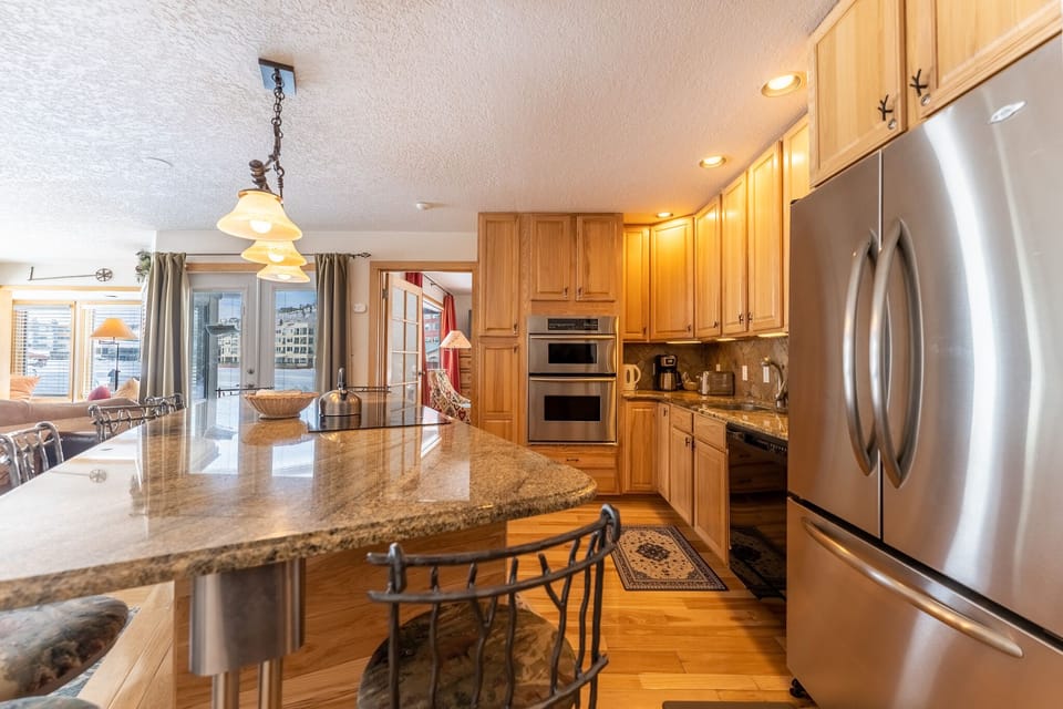 Cook your favorite meals in this spacious, fully-equipped kitchen featuring granite countertops, stainless steel appliances, and warm wood cabinetry.