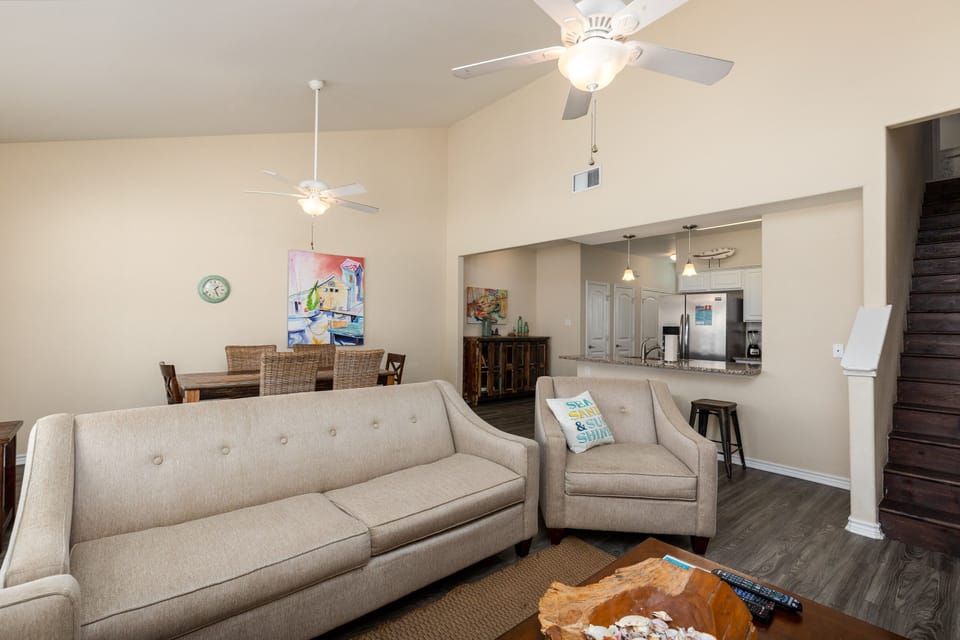 Relax in your spacious open-concept living area with comfortable seating, ceiling fans, and seamless flow to the fully equipped kitchen.