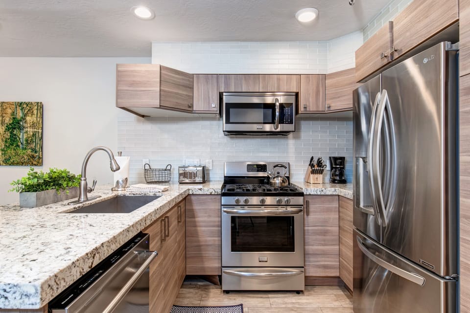 New kitchen with custom cabinets, stainless appliances, 6-burner gas stove, granite counters, and 3 bar seats