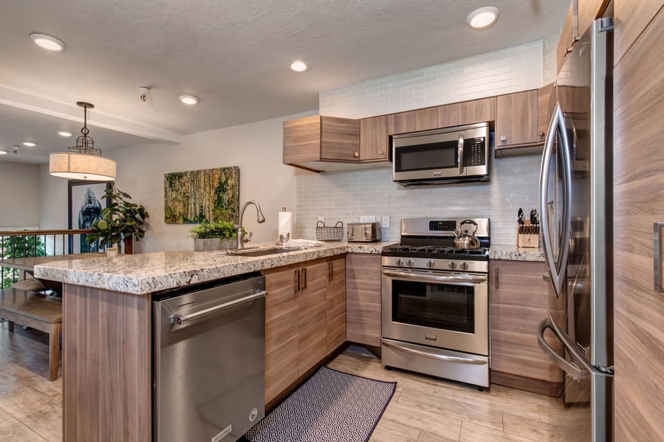 New kitchen with custom cabinets, stainless appliances, 6-burner gas stove, granite counters, and 3 bar seats
