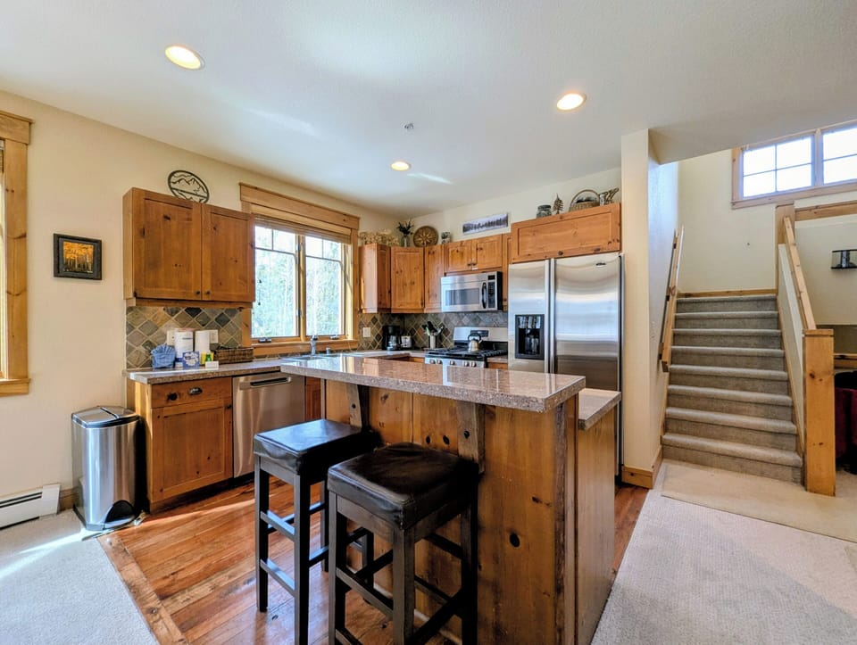 Your spacious kitchen awaits with warm wood cabinetry, granite countertops, and a breakfast bar perfect for morning coffee and casual meals.