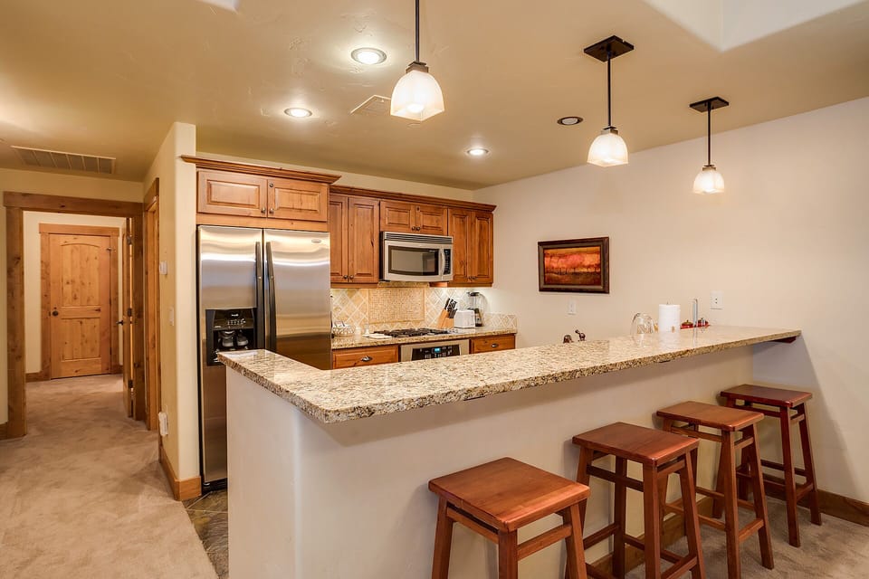 Your fully equipped kitchen awaits with granite counters, stainless appliances, and a breakfast bar perfect for morning coffee or evening conversations.