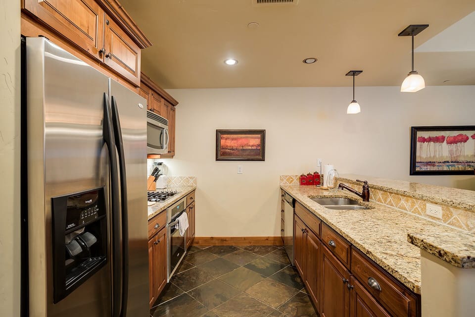 Your gourmet kitchen awaits with granite countertops, stainless steel appliances, and warm wood cabinetry perfect for preparing memorable meals.