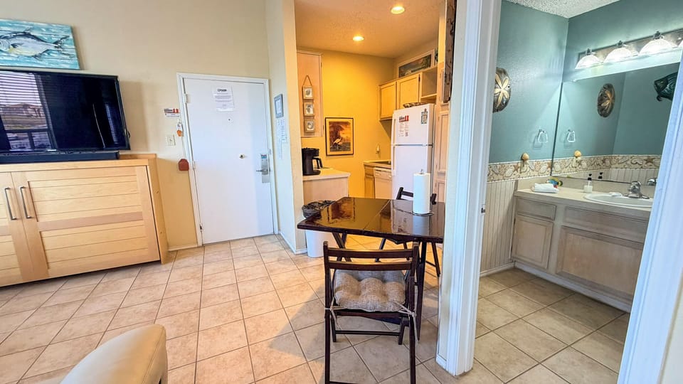 Your cozy coastal retreat features an open layout with kitchen, dining space, and glimpse of the bathroom—perfect for unwinding.