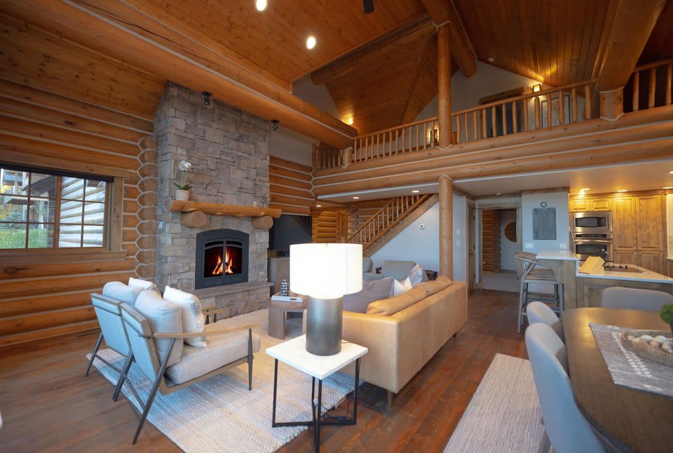 Step into your cozy mountain retreat where warm wood beams frame soaring ceilings and a crackling stone fireplace invites you to unwind with loved ones in comfort.