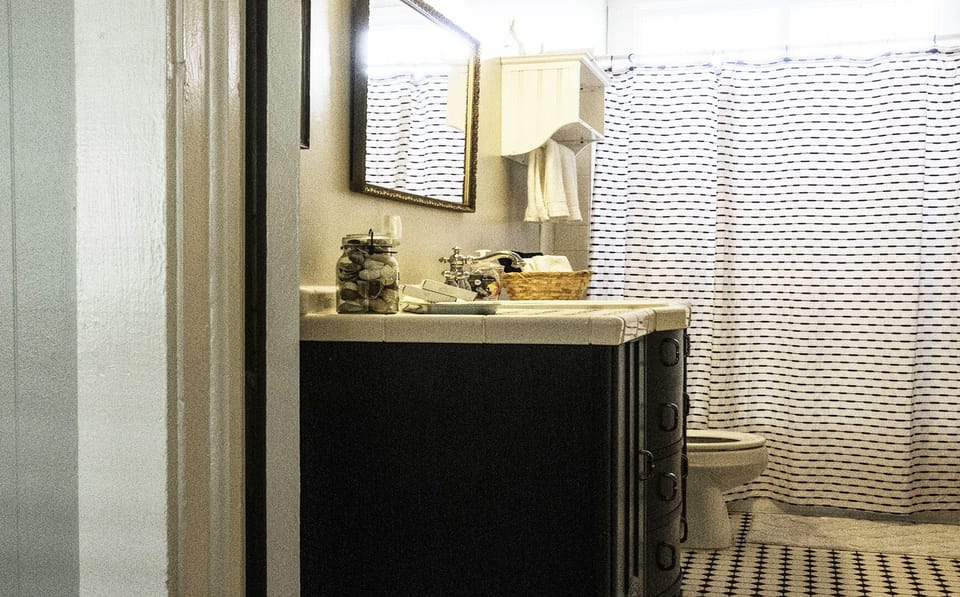 FUll bathroom attached to primary queen bedroom #1 - The primary full bath, attached to primary queen bedroom #1, shines with its classic black-and-white tile floor, a convenient tub/shower combo, and a vanity sprinkled with special touches.