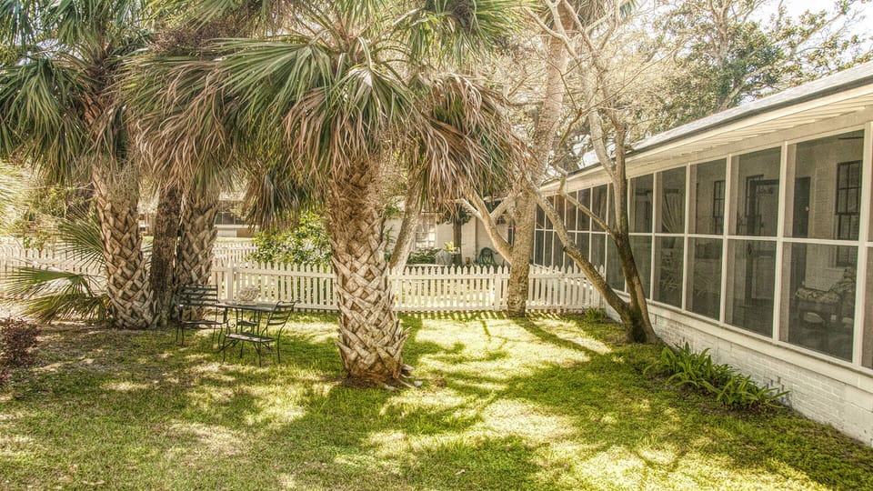 View of home exterior and yard - The wraparound screened porch offers breezy Tybee charm, a relaxing place to sip sweet tea or read, and it’s pet-friendly.