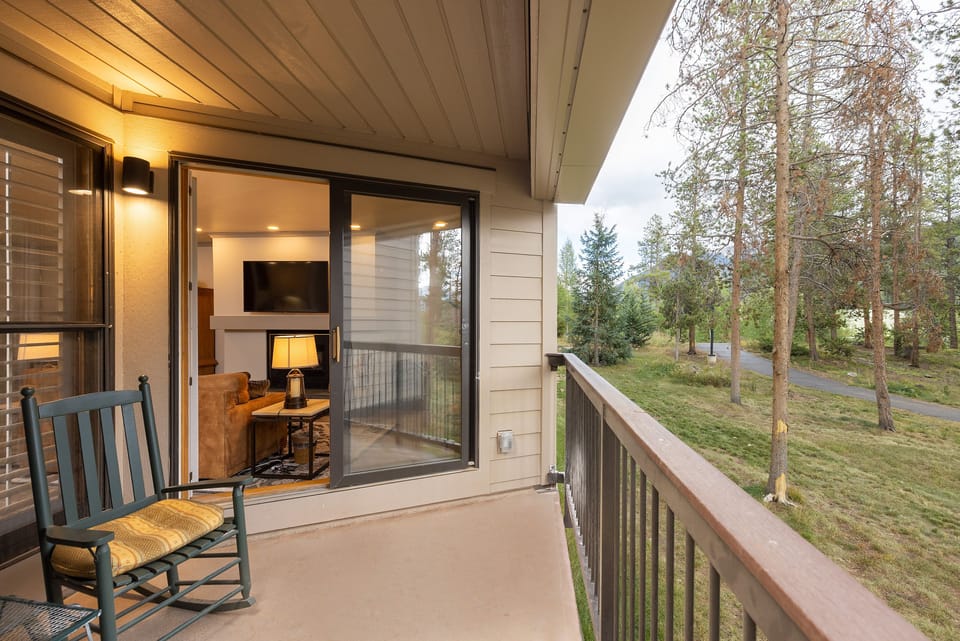 Unwind on your private balcony with forest views, where evening light filters through trees as you rock gently in your chair.
