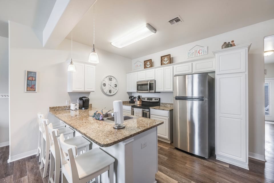 Your bright modern kitchen awaits with granite counters, stainless appliances, and a breakfast bar perfect for morning coffee or evening meals together.