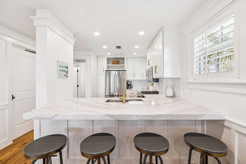 Your gourmet kitchen awaits with stunning marble island, stainless steel appliances, and bright natural light streaming through plantation shutters.