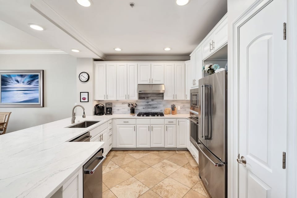 Step into your fully-equipped kitchen, where sleek white cabinetry and gleaming countertops invite you to whip up homemade meals. Stainless appliances and modern touches make cooking a breeze during your stay.