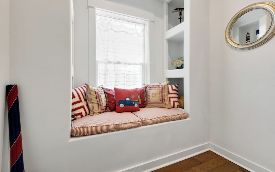Curl up in your charming window nook with soft cushions and playful pillows, perfect for reading or simply watching the world go by.