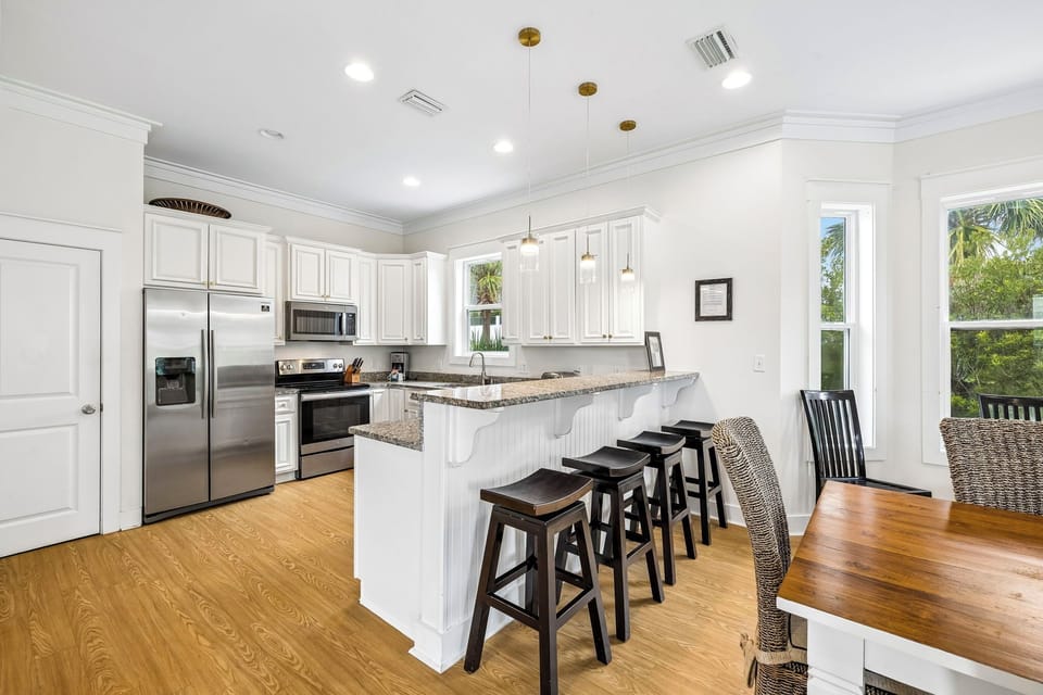 Gather around the bright, open kitchen where modern appliances meet classic coastal charm. Spacious granite counters and a welcoming breakfast bar make meal prep a breeze.