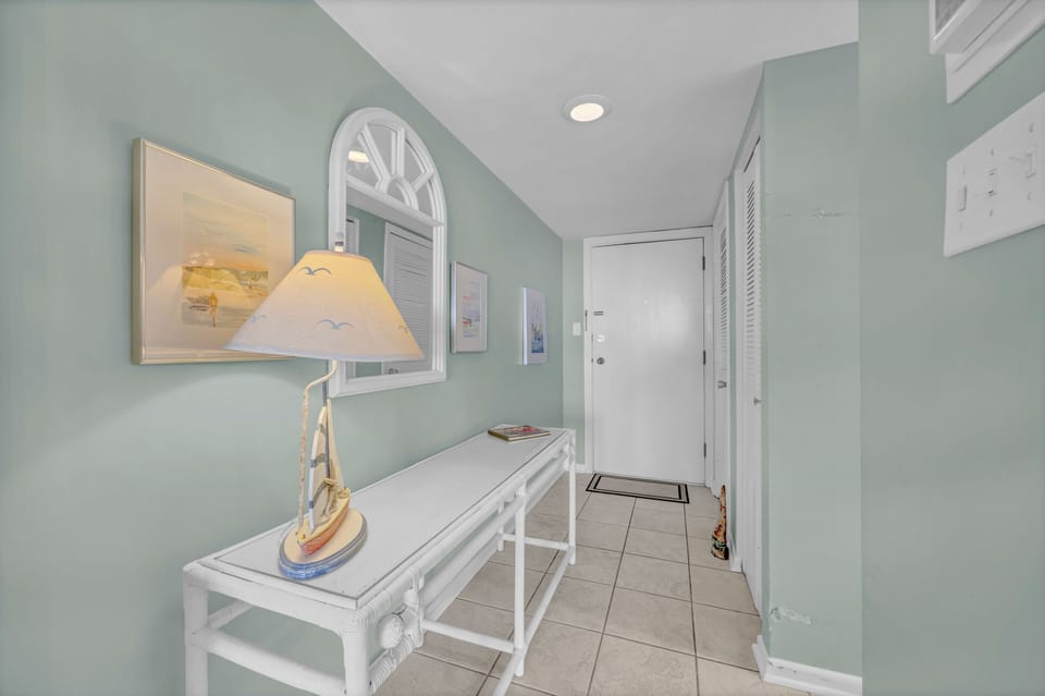 Step into your coastal haven through this bright, inviting entryway with breezy beach-inspired decor and soothing seafoam walls that welcome you home.