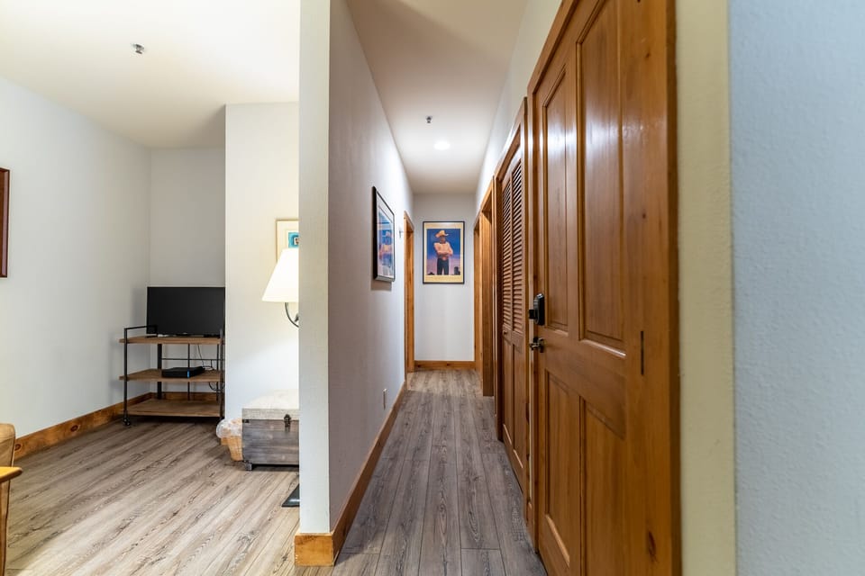 Your warm hallway connects cozy living spaces with rich wood accents and charming artwork throughout.
