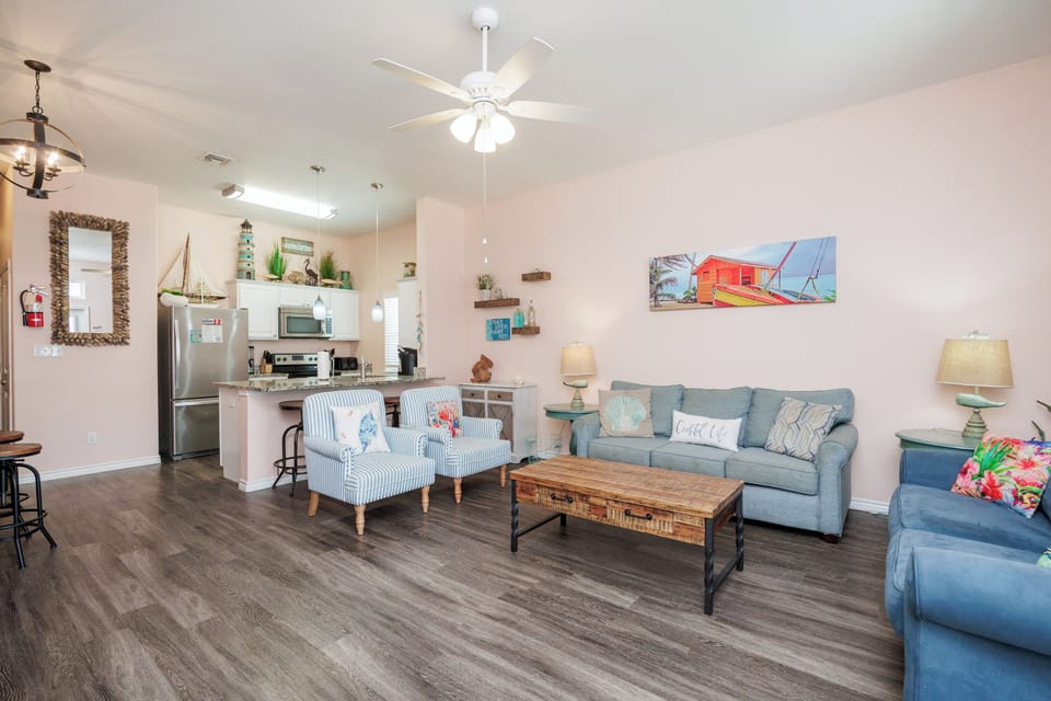 Relax in your bright coastal-themed living space with comfortable seating, a sleeper sofa, and a fully equipped kitchen ready for your vacation meals.