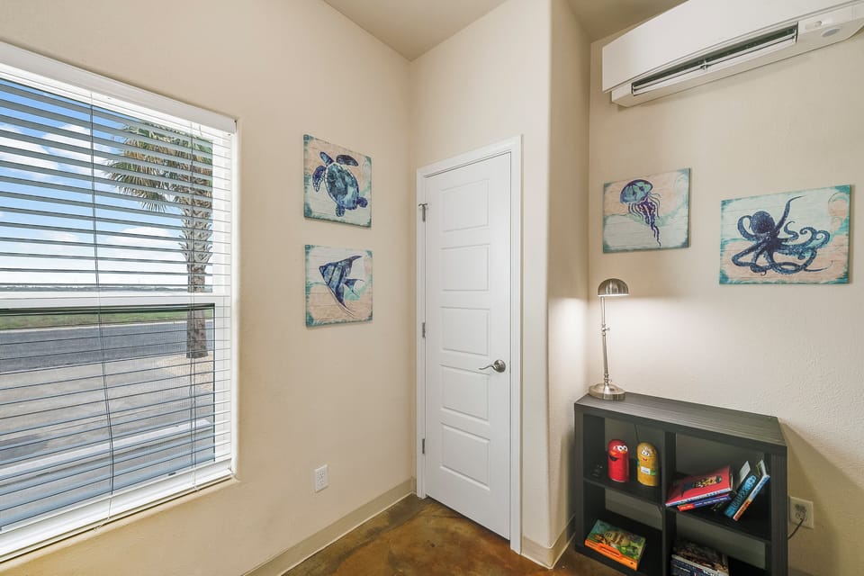 Your cozy reading nook awaits with nautical artwork, natural light, and a bookshelf stocked with vacation reads.
