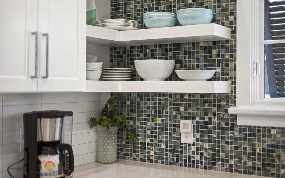 Your fully equipped kitchen features elegant open shelving with quality dishes and a stylish mosaic backsplash for your culinary adventures.