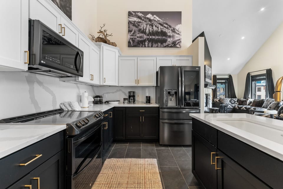 Cook like a chef in your sleek kitchen featuring dark cabinetry, brass accents, and modern stainless steel appliances.
