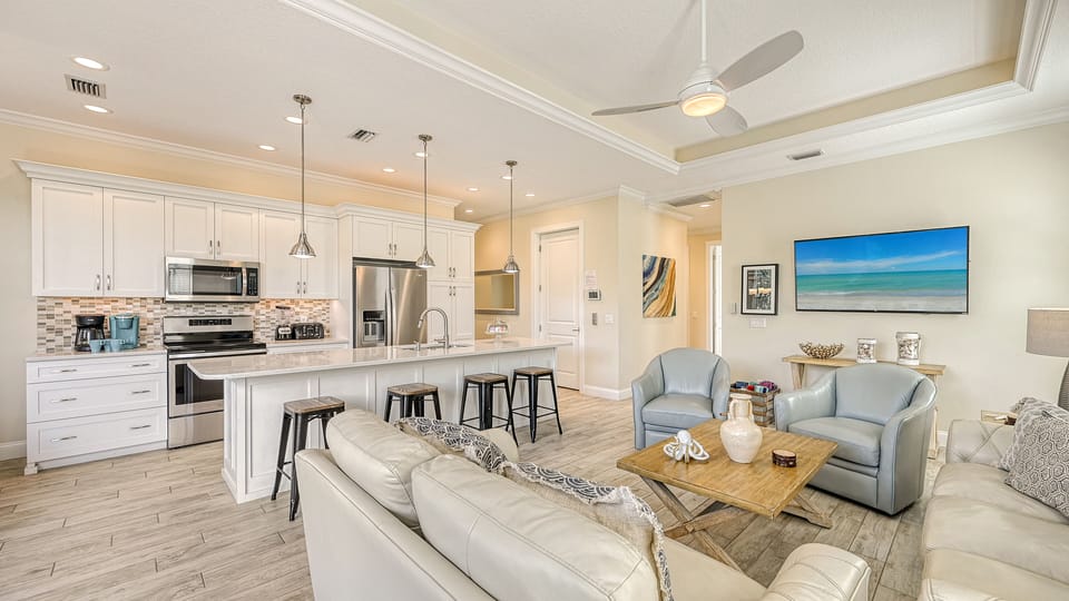 Bask in the open flow of this inviting space—where lively conversations start at the breakfast bar and cozy sofas await your unwind after a day in the sun.