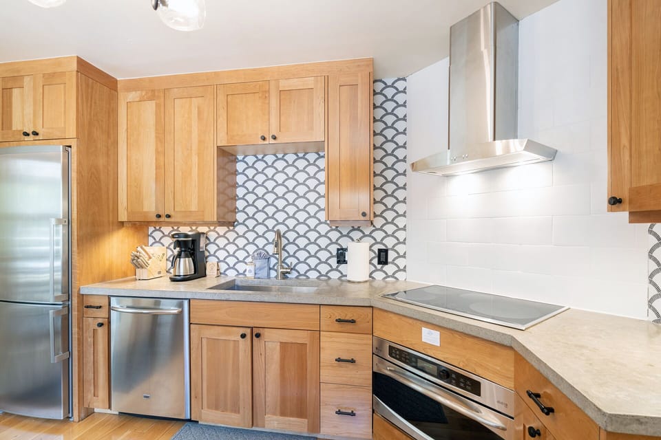 The kitchen features custom cabinetry, stainless appliances & a concrete countertop. It is also fully equipped with all of the basic supplies for your stay!