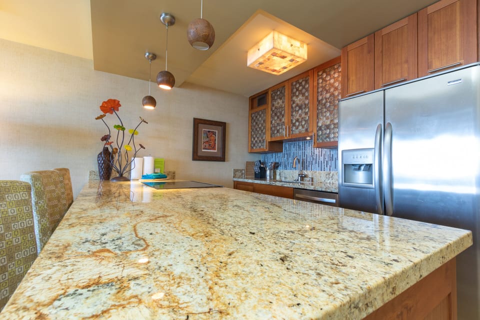 Picture yourself preparing morning coffee at this stunning granite island, where modern stainless appliances meet warm wood cabinetry and stylish pendant lighting creates the perfect ambiance for your vacation cooking.