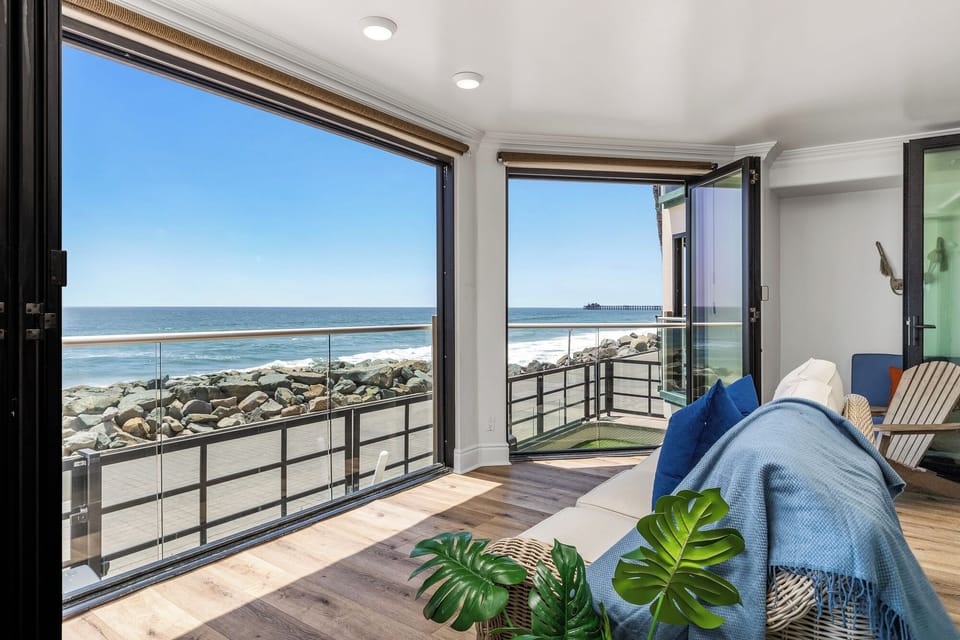 Perfect Place to Lay Back and Watch as the Sun Sets space, where floor-to-ceiling windows frame endless blue waters and golden sand.