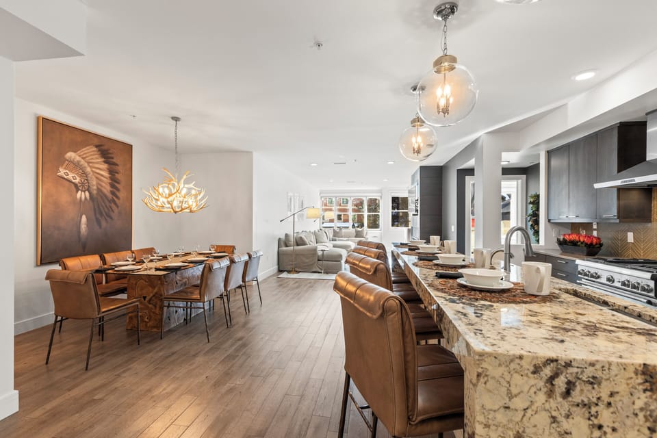 The open concept kitchen and dining area are highlighted by warm leather, wood floors and stylish art.