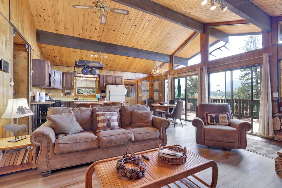 Cozy mountain living room with wood ceilings, stone fireplace, comfy seating, and smart TV—perfect for relaxing evenings, movie nights, and warm cabin vibes after outdoor adventures.