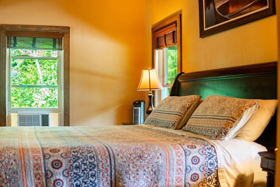 Main floor master ensuite bedroom 1 with A/C in summer, ceiling fan, TV, big windows, and king-sized bed.