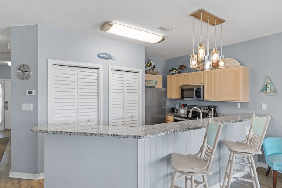 Gather around your spacious kitchen peninsula where granite counters and coastal decor create the perfect spot for morning coffee or evening conversations.