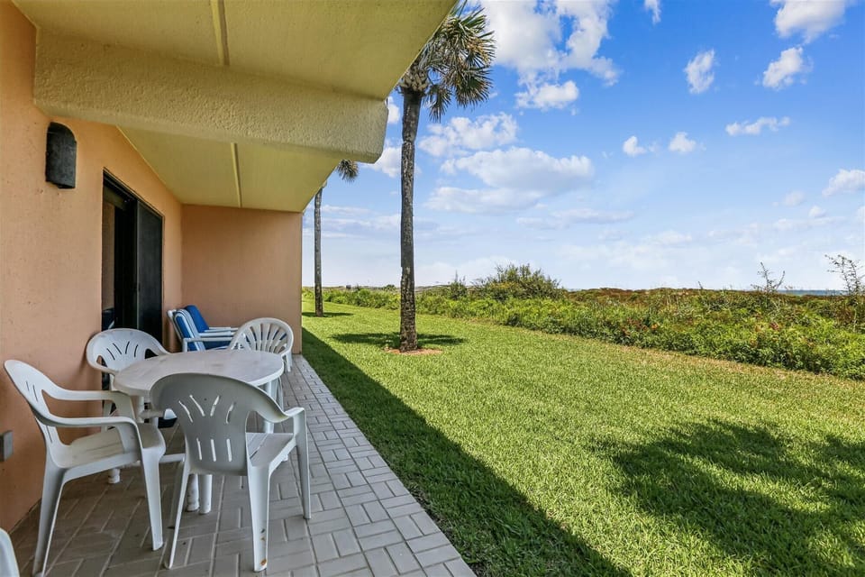 - Patio dining table and chairs overlooking grassy lawn  
- Relax in shade or sunshine with coastal breezes nearby  
- Perfect setup for outdoor meals and evening relaxation 