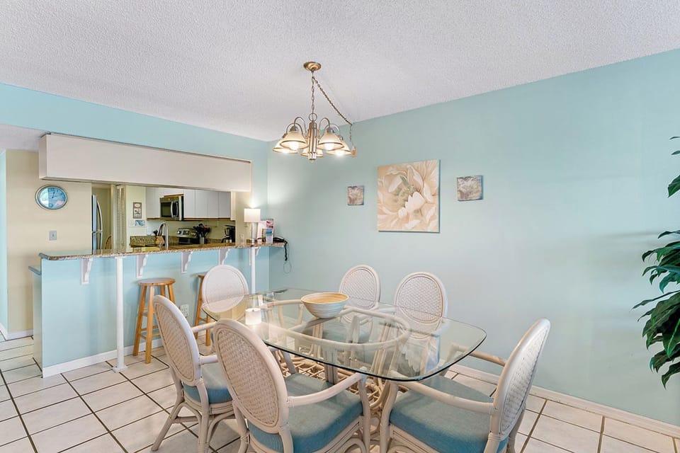 Gather around your elegant glass dining table for memorable meals in this bright, airy space with soothing mint walls and coastal charm.