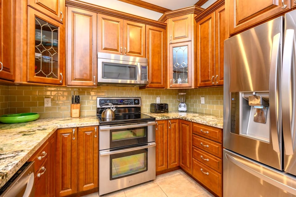 Modern kitchen with stainless appliances, granite counters, and warm cabinetry.