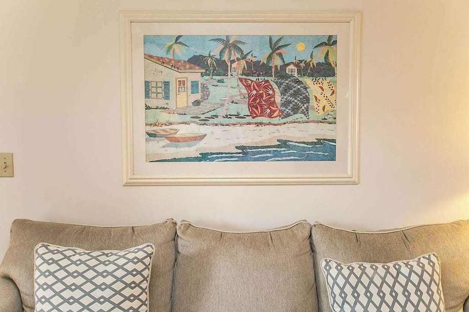 - Framed coastal artwork adds charm and color to the living room environment
- Positioned above the sofa creating a balanced and stylish wall display
- Reflects the beach inspired decor that carries throughout the home
