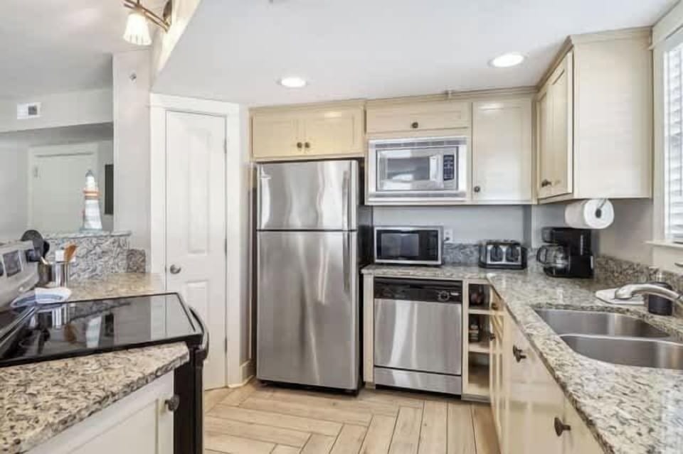 The fully outfitted kitchen looks out over balcony with stainless appliances & granite countertops.