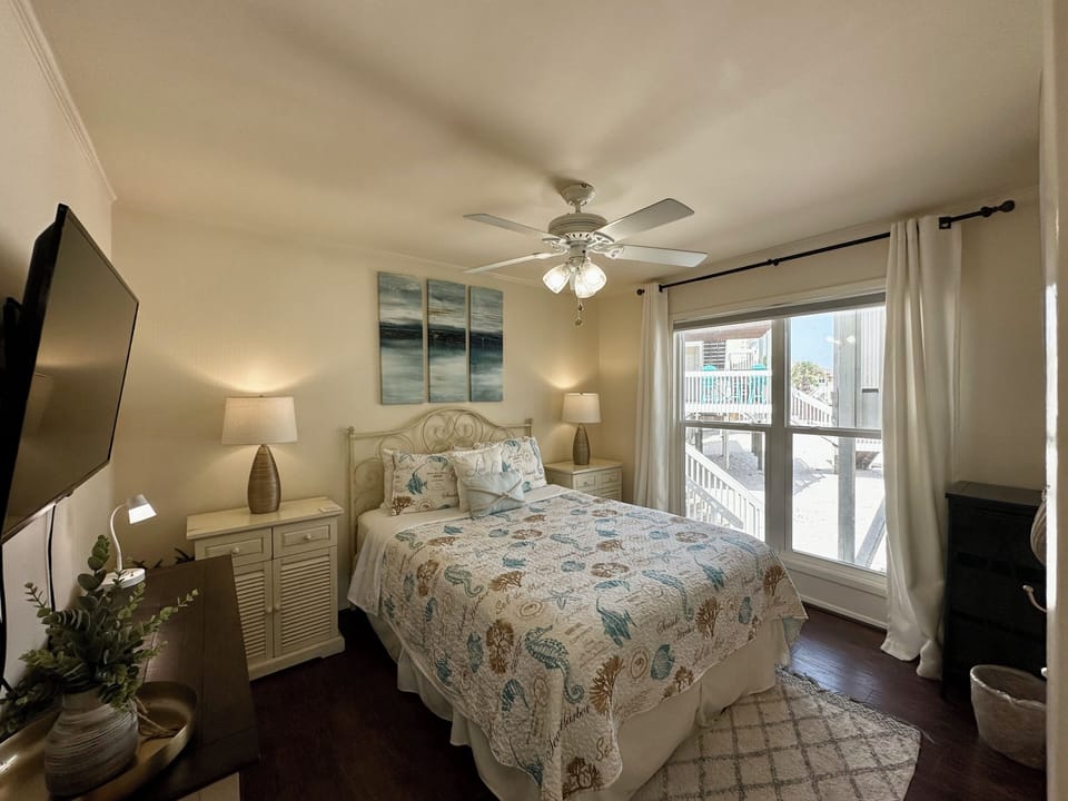 Sink into coastal comfort in your serene bedroom, where ocean hues and soft linens invite restful nights beneath the gentle ceiling fan.