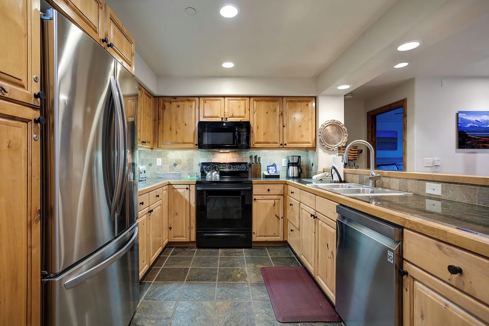 Your fully equipped kitchen features warm wood cabinets and stainless appliances, perfect for preparing meals during your mountain getaway.