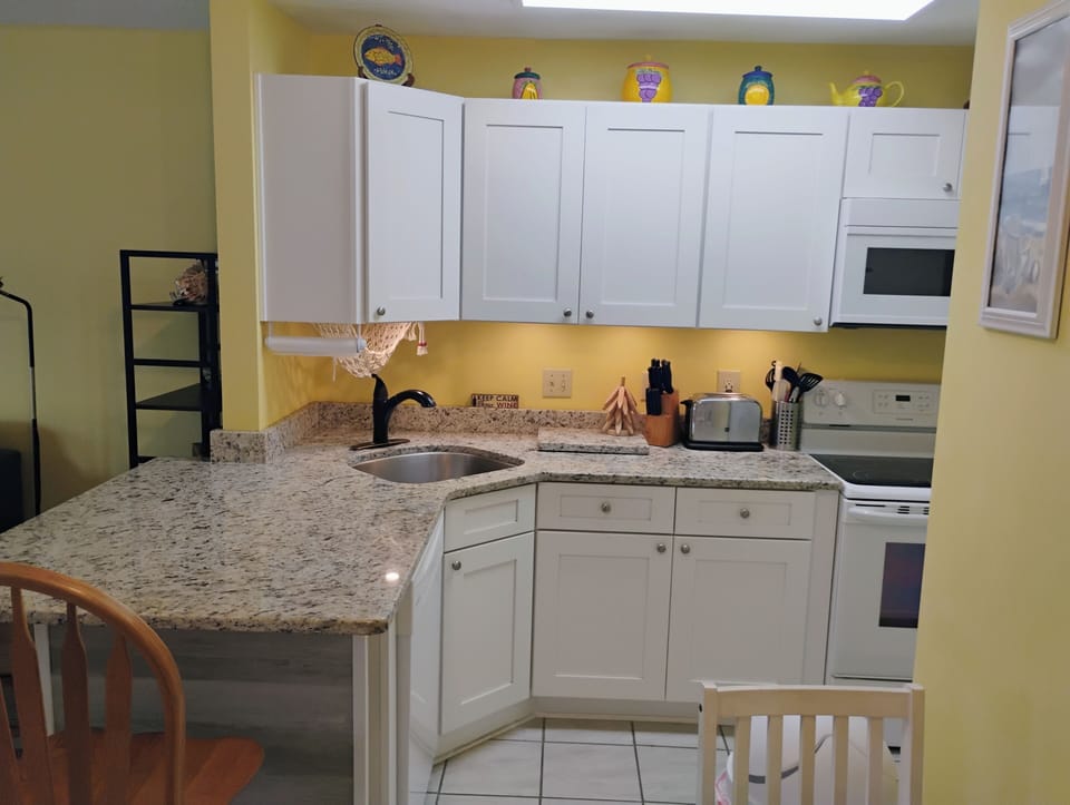 Your bright, cheerful kitchen offers granite counters, white cabinets, and everything you need to prepare meals during your stay.