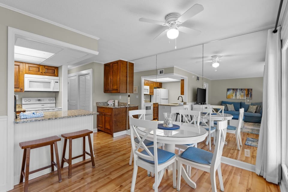 Gather around this bright, open dining and kitchen space where warm wood floors and coastal blue accents create a welcoming atmosphere for your vacation meals and memories.