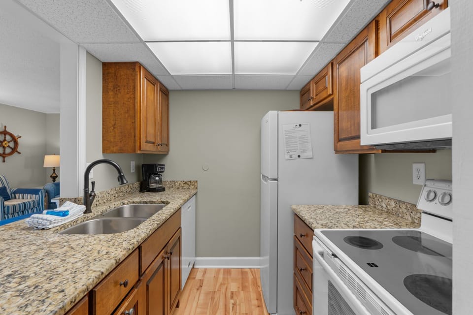 Your fully equipped kitchen awaits, featuring warm wood cabinetry, granite countertops, and all the essentials you need to prepare delicious meals during your stay.